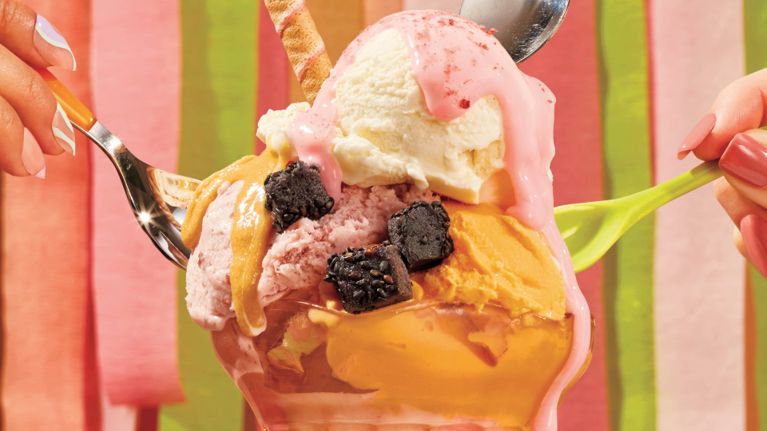 An ice cream sundae with strawberry sauce and small cubes of black sesame butter mochi.