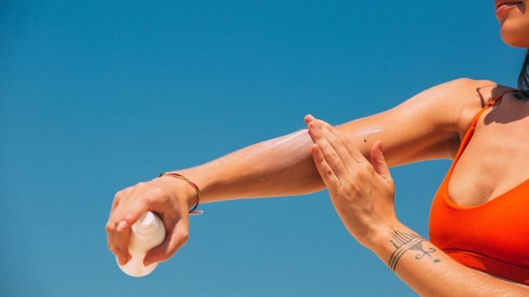 Photo of a person applying sunscreen on their forearm with a blue sky background. Photo by: Mikhail Nilov on Pexels.