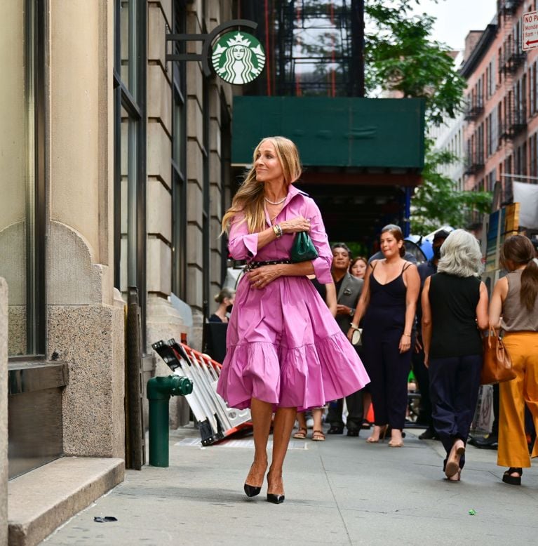 A woman in a bright pink dress strutting down the street in a post on main character energy.