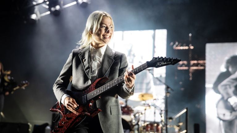 Phoebe Bridgers playing the guitar on stage. Photo by Getty Images